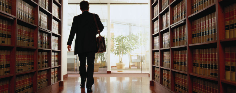 A lawyer walking between rows of law books